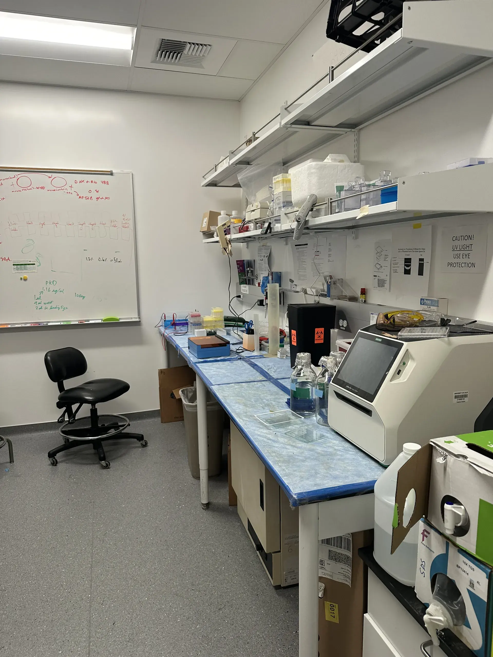 An instrument bench beside a whiteboard, an analyser at the end of the run