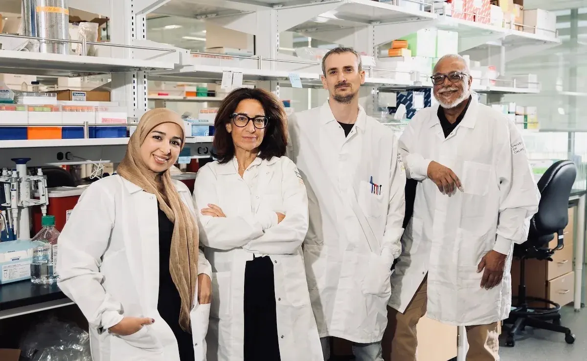 Karine Le Roch with three members of the lab, in white coats at the bench